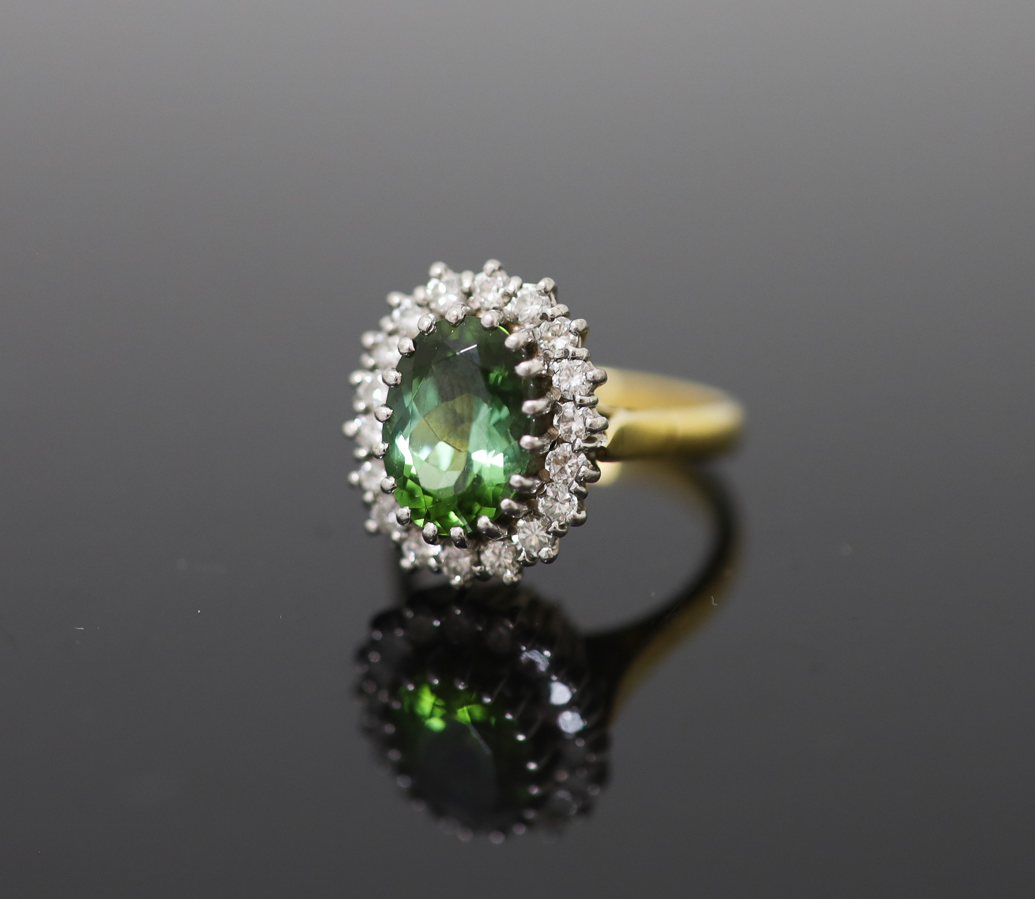 A modern 18ct gold, green tourmaline and diamond set oval cluster ring